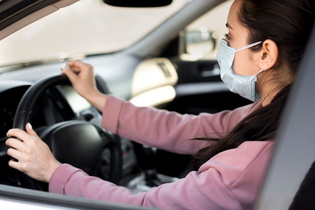 Foto gratuita mujer con máscara dentro de su propio automóvil