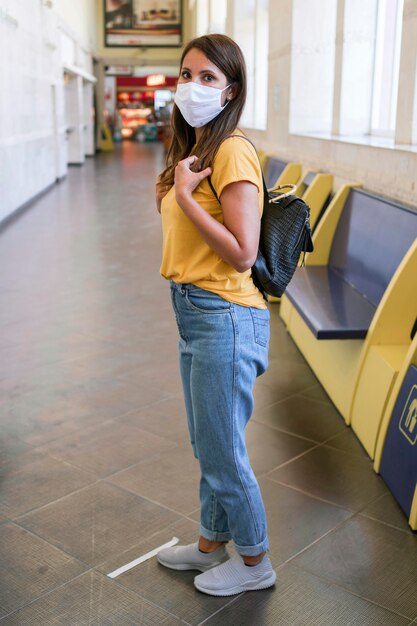 Mujer con máscara y esperando el transporte público