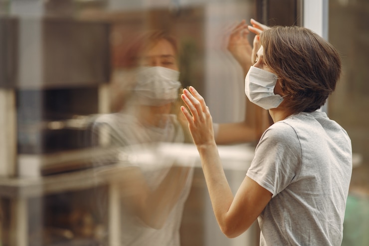 Foto gratuito mujer en una máscara está junto a la ventana