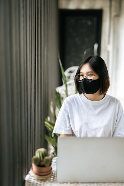 Foto gratuita una mujer con una máscara y jugando un ordenador portátil.
