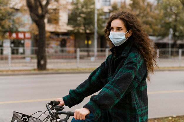 Mujer con máscara médica y andar en bicicleta