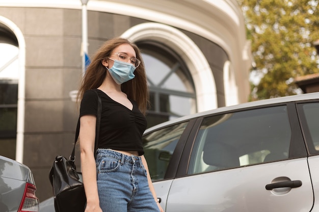 Foto gratuita mujer con máscara médica caminando por la ciudad