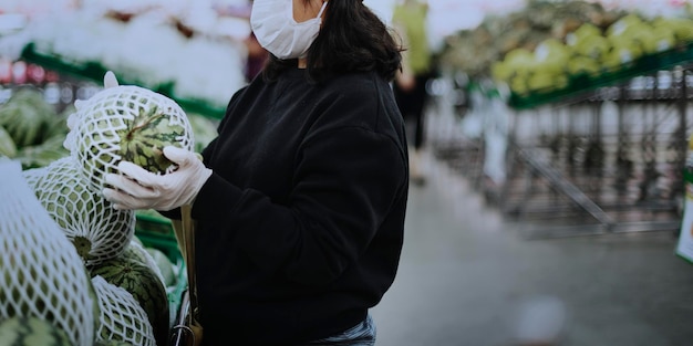 Mujer con máscara médica comprando alimentos frescos durante la pandemia de coronavirus