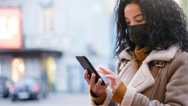 Mujer con máscara médica comprobando su teléfono