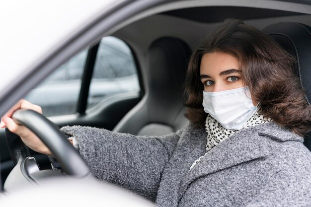 Mujer con máscara médica conduciendo coche