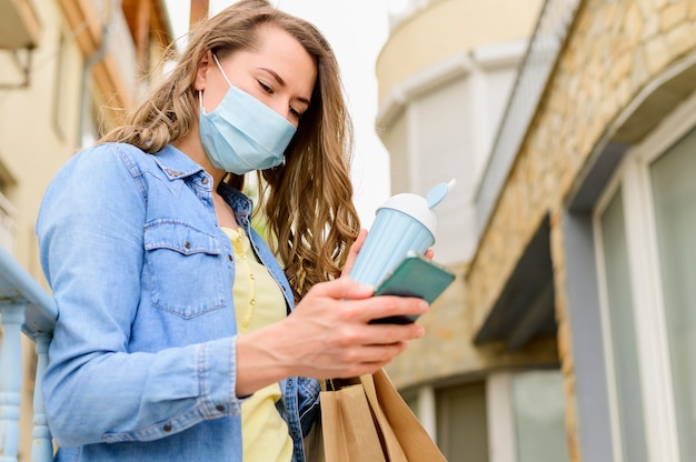 Mujer con máscara médica, navegar por teléfono móvil