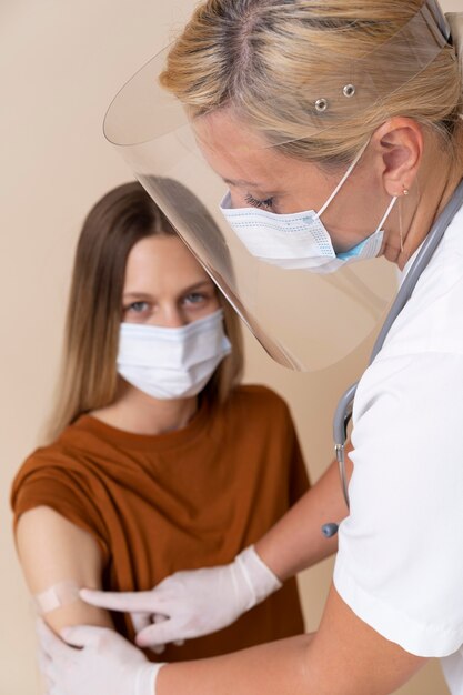 Mujer con máscara médica obteniendo una pegatina en el brazo después de recibir una vacuna
