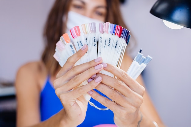 Foto gratuita mujer con máscara médica protectora en el salón de belleza, sostenga la paleta y seleccione un color procedimiento de manicura cuidado de las uñas gran inauguración la cuarentena ha terminado las pequeñas empresas están abiertas nuevamente