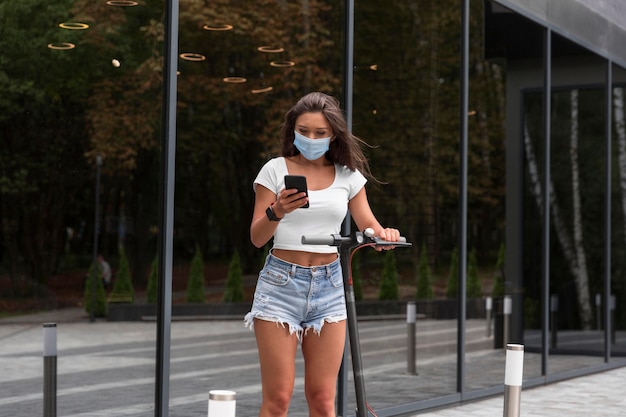 Mujer con máscara médica y scooter al aire libre