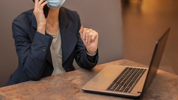 Mujer con máscara médica trabajando en equipo portátil