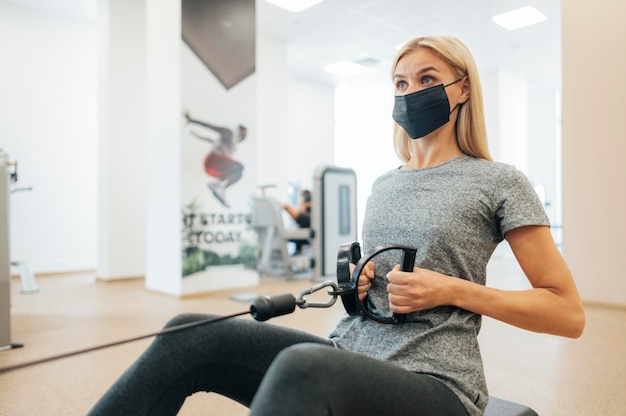 Mujer con máscara médica trabajando en el gimnasio