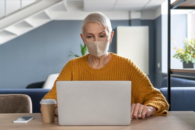 Foto gratuita mujer con máscara médica trabajando