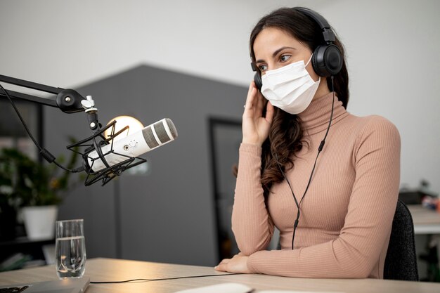 Mujer con máscara médica transmitiendo por radio