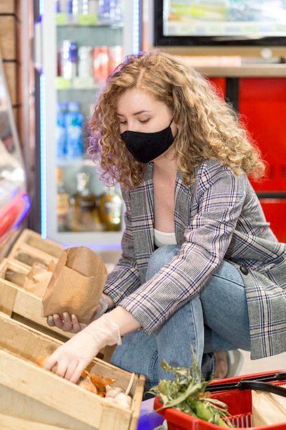 Mujer con máscara en el mercado de comestibles de compras