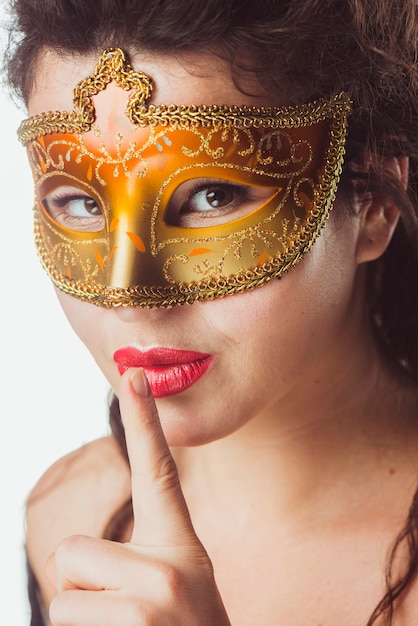 Mujer en máscara de oro gesticular silencio
