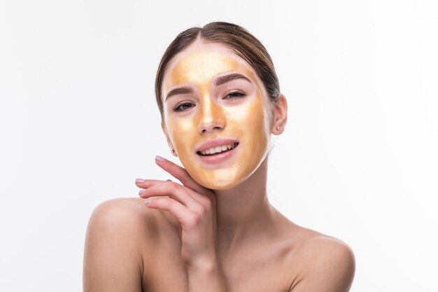 Mujer con máscara de oro. Hermosa mujer con máscara de oro en la piel de la cara toque cosmético Cara. Belleza Cuidado de la piel y tratamiento