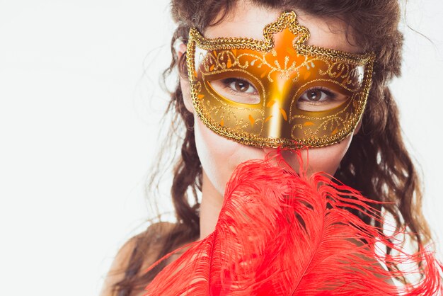 Mujer en máscara de oro con plumas rojas