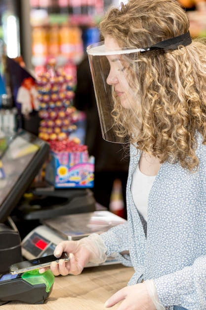 Mujer con máscara pagando comestibles