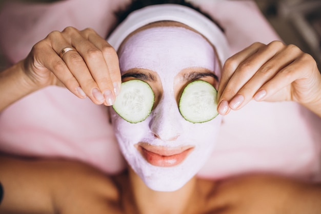 Mujer con máscara y pepino en los ojos