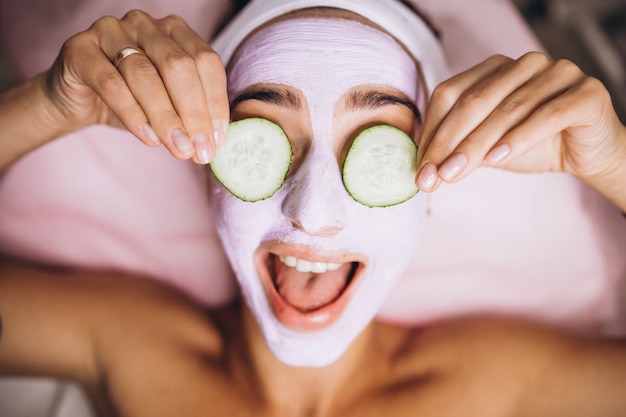 Mujer con máscara y pepino en los ojos