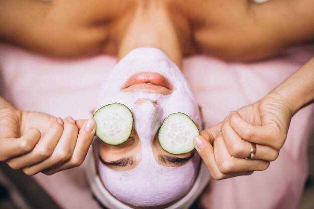 Mujer con máscara y pepino en los ojos