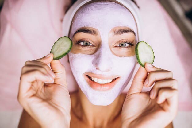 Mujer con máscara y pepino en los ojos