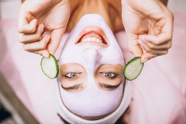 Mujer con máscara y pepino en los ojos