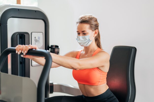 Mujer con máscara trabajando en el gimnasio