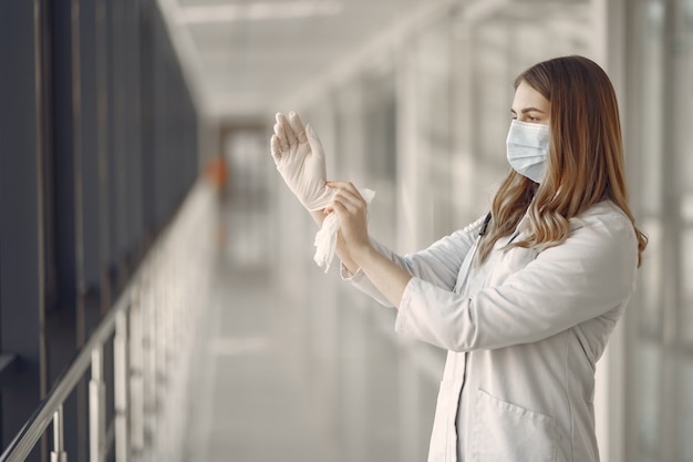 Mujer en una máscara y uniforme se pone guantes