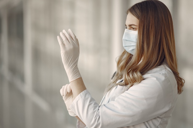 Mujer en una máscara y uniforme se pone guantes