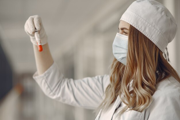 Mujer en una máscara y uniforme sosteniendo un tubo en sus manos