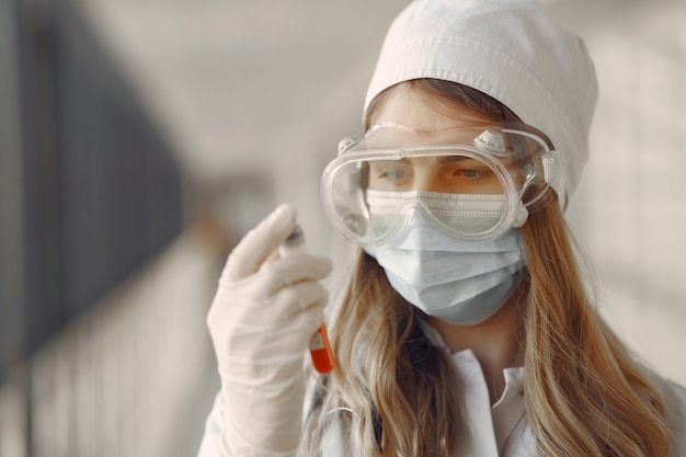 Foto gratuita mujer en una máscara y uniforme sosteniendo un tubo en sus manos