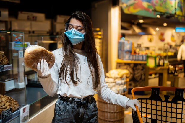 La mujer con mascarilla va a comprar pan