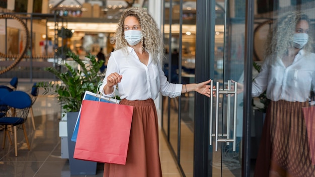 Mujer, con, mascarilla, proceso de llevar, bolsas de compras