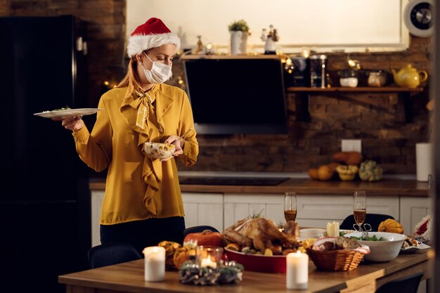 Mujer con mascarilla protectora poniendo mesa de comedor para la cena de Navidad