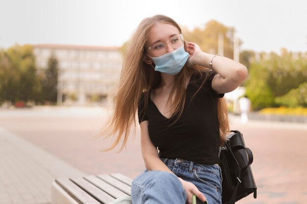 Mujer con mascarilla sentada en un banco