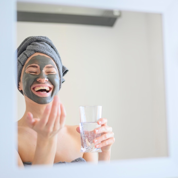 Foto gratuita mujer con mascarilla sonriente en el espejo