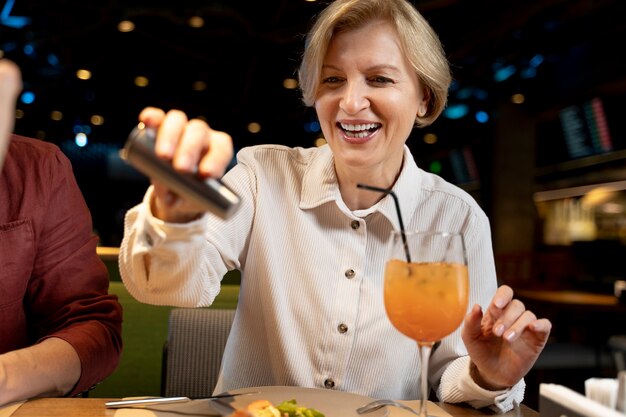 Mujer mayor agregando sal a su comida en un restaurante