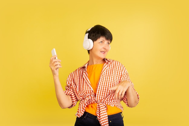 Mujer mayor aislada en amarillo. Tecnología y concepto de estilo de vida de ancianos alegre