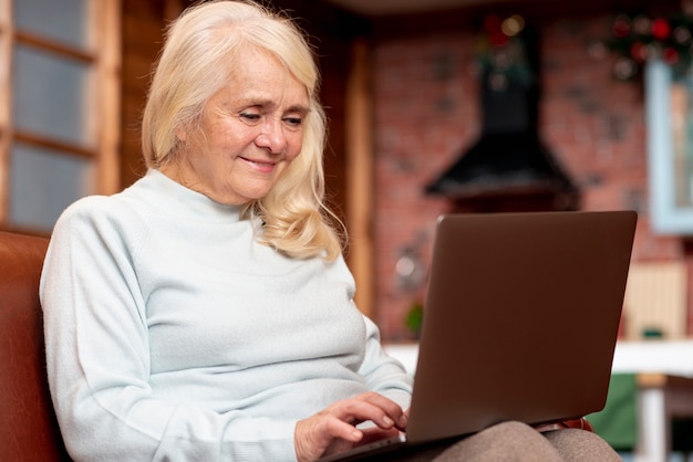 Mujer mayor de ángulo bajo usando laptop