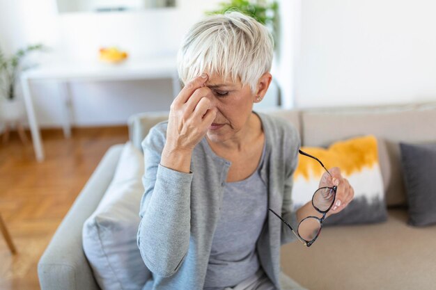 Mujer mayor con anteojos se frota los ojos que sufren de ojos cansados concepto de enfermedades oculares