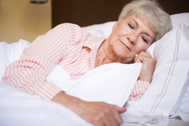 Mujer mayor cansada en la cama