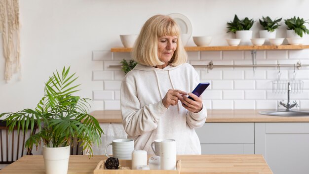 Mujer mayor en casa con smartphone