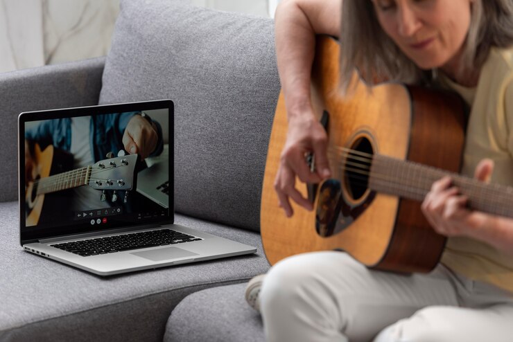 Foto gratuito mujer mayor en casa en el sofá con laptop para lecciones de guitarra