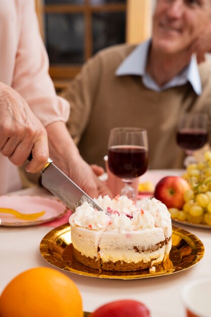 Mujer mayor cortando pastel y divirtiéndose en la fiesta