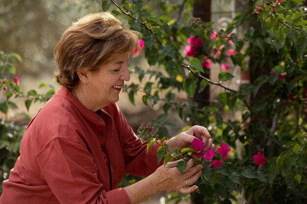 Mujer mayor disfrutando de la naturaleza en el jardín de su casa rural