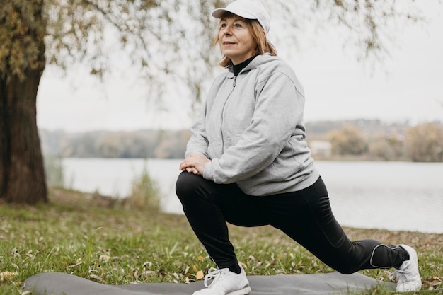 Foto gratuita mujer mayor, ejercitar, aire libre, en, mat