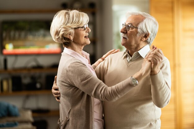 Mujer mayor feliz bailando con su esposo en casa