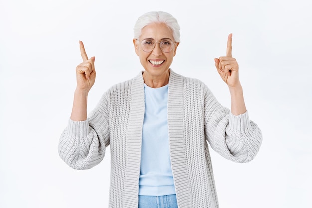 Mujer mayor feliz despreocupada, sonriente con el pelo gris, gafas recetadas y chaqueta de punto