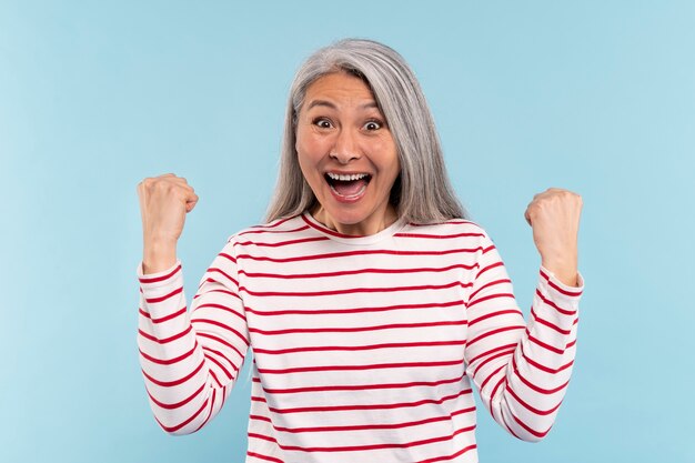 Mujer mayor feliz y emocionada contra un fondo azul